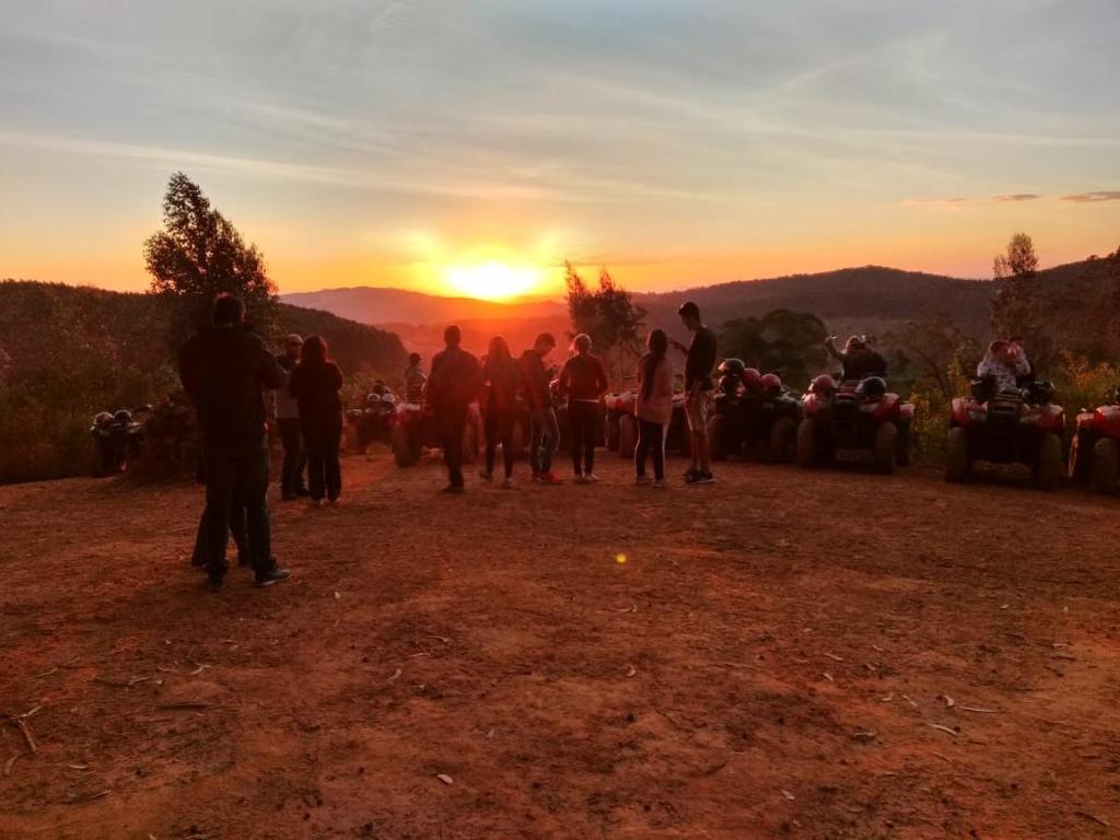 um grupo de pessoas em pé ao redor assistindo o pôr do sol em Chales Fazenda Cantinho do Selado em Monte Verde