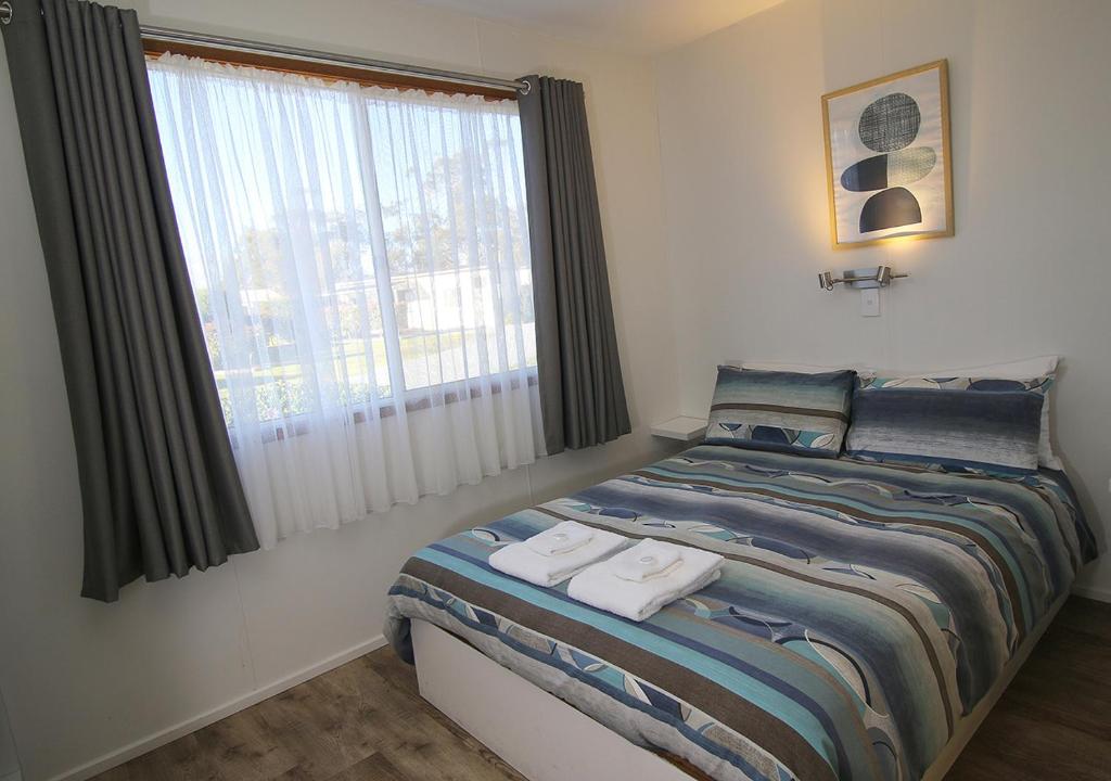 a bedroom with a bed with two towels on it at Beauty Point Tourist Park in Beauty Point