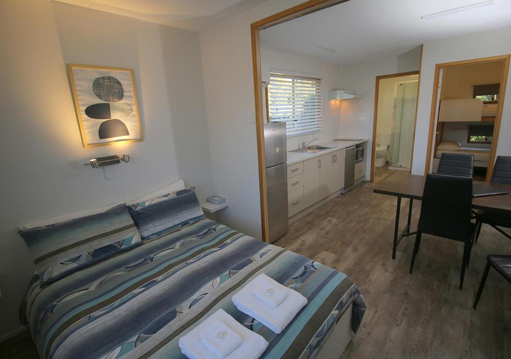 a bedroom with a bed and a kitchen and a table at Beauty Point Tourist Park in Beauty Point