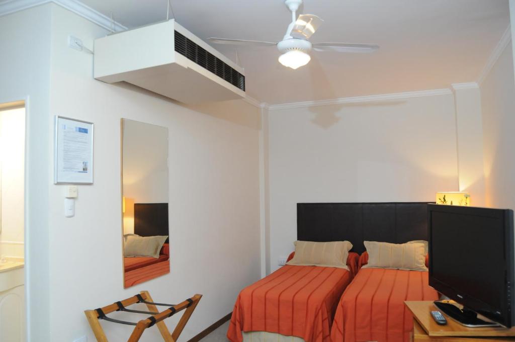 Schlafzimmer mit einem Bett, einem TV und einem Schreibtisch in der Unterkunft Parra Hotel & Suites in Rafaela