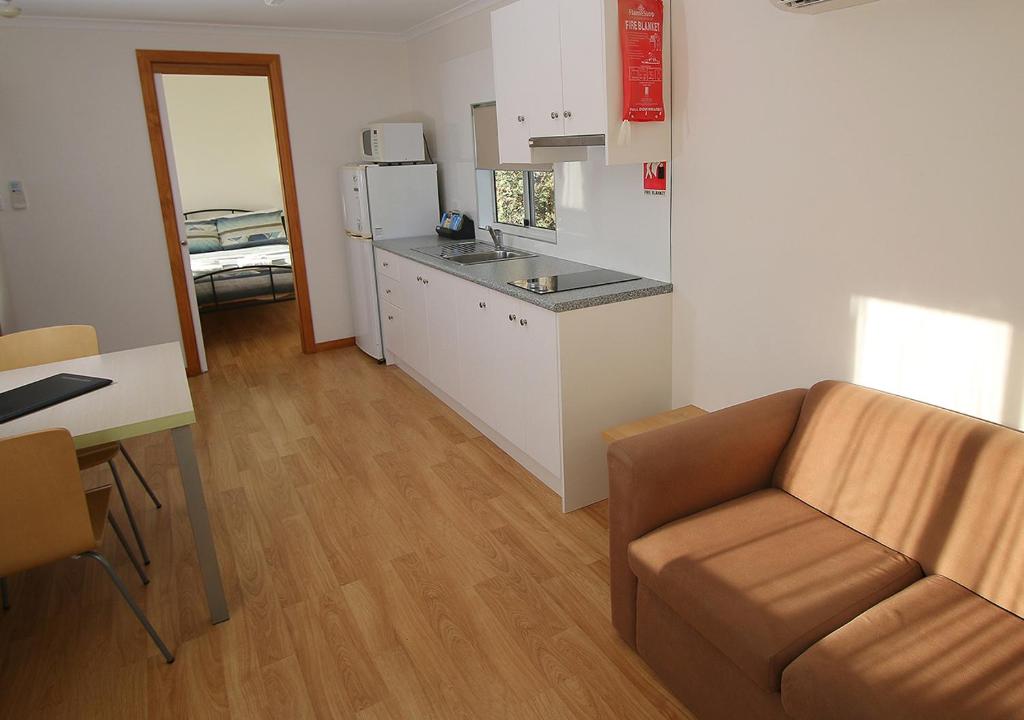 a living room with a couch and a kitchen at Beauty Point Tourist Park in Beauty Point