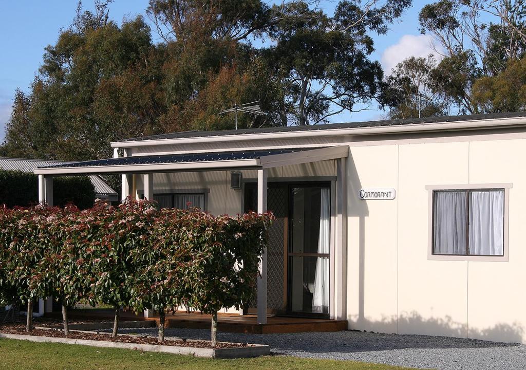 a white house with a bush in front of it at Beauty Point Tourist Park in Beauty Point