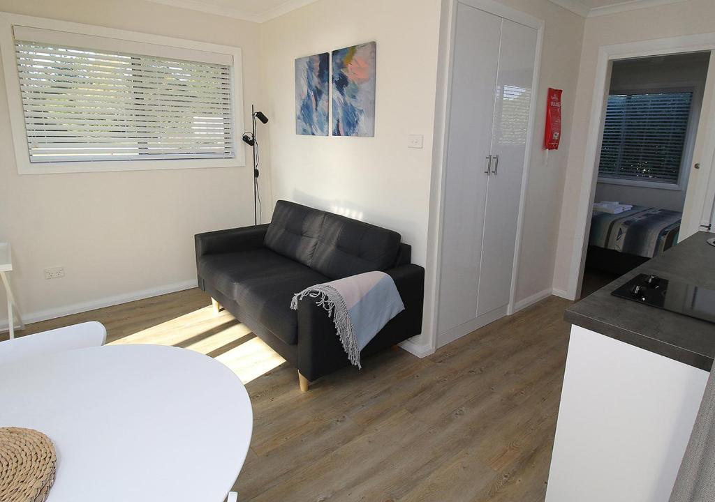a living room with a black couch and a kitchen at Beauty Point Tourist Park in Beauty Point