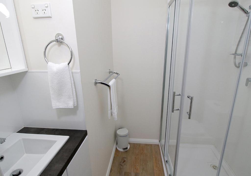 a white bathroom with a shower and a sink at Beauty Point Tourist Park in Beauty Point