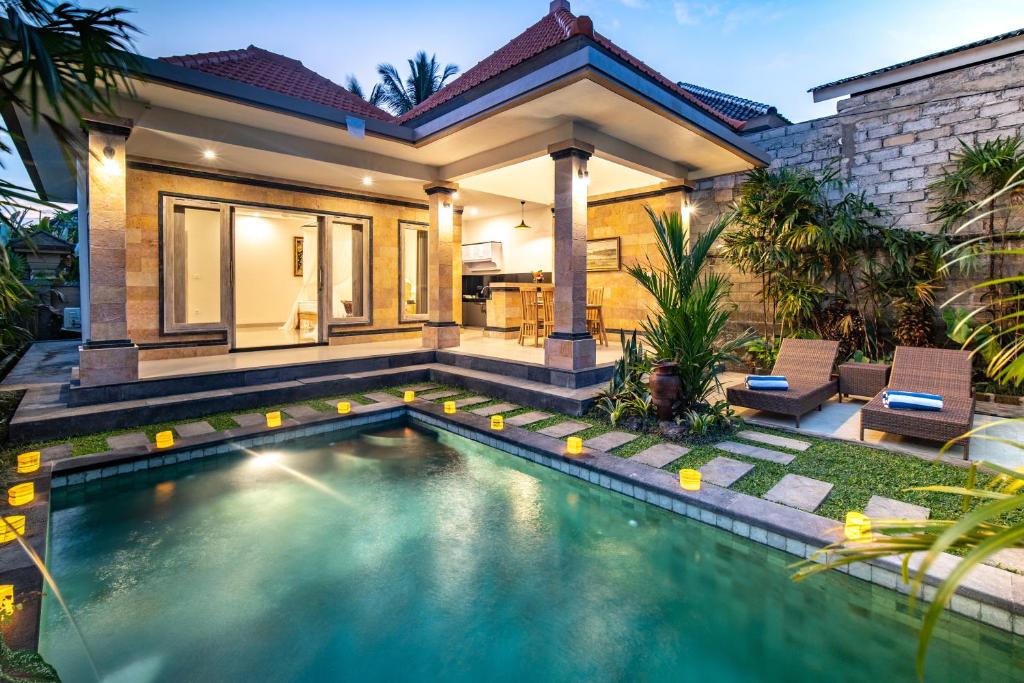 a swimming pool in front of a house at Puri Sedana Ubud Villa in Ubud