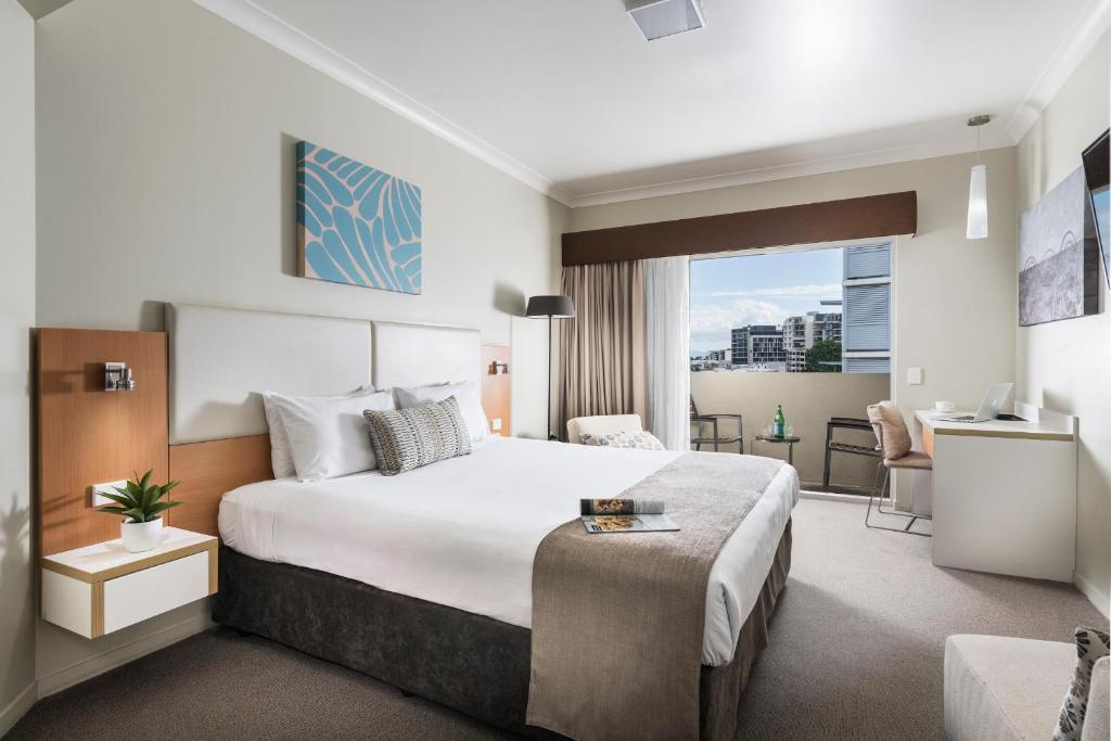 ein Hotelzimmer mit einem Bett und einem Schreibtisch in der Unterkunft Grand Hotel and Apartments Townsville in Townsville