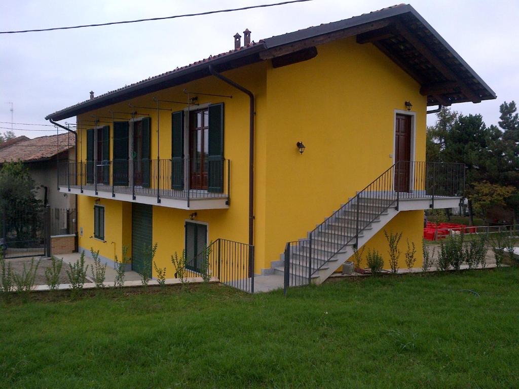 una casa amarilla con una escalera delante de ella en Casetta San Giovanni, en Barolo