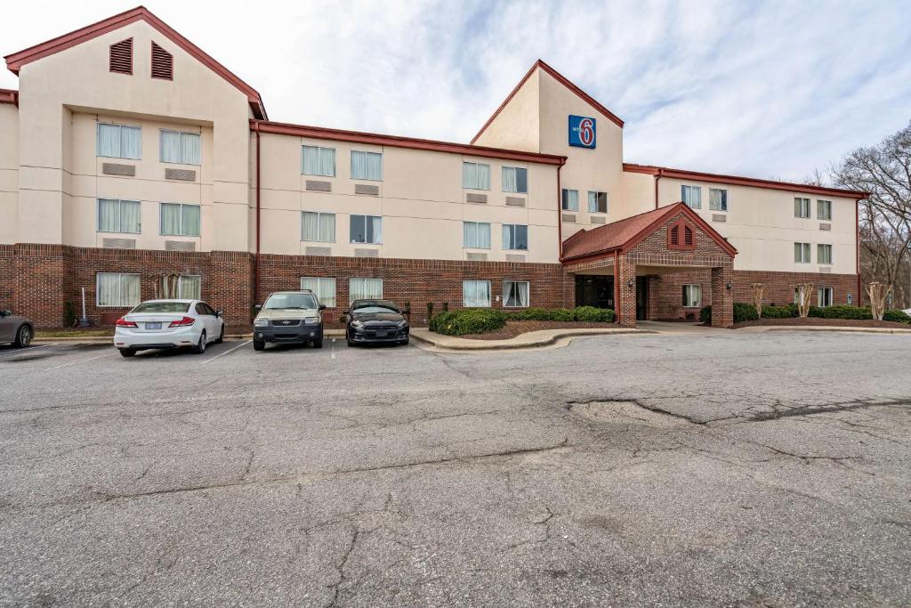 un gran edificio con coches estacionados en un estacionamiento en Motel 6-Rocky Mount, NC, en Rocky Mount