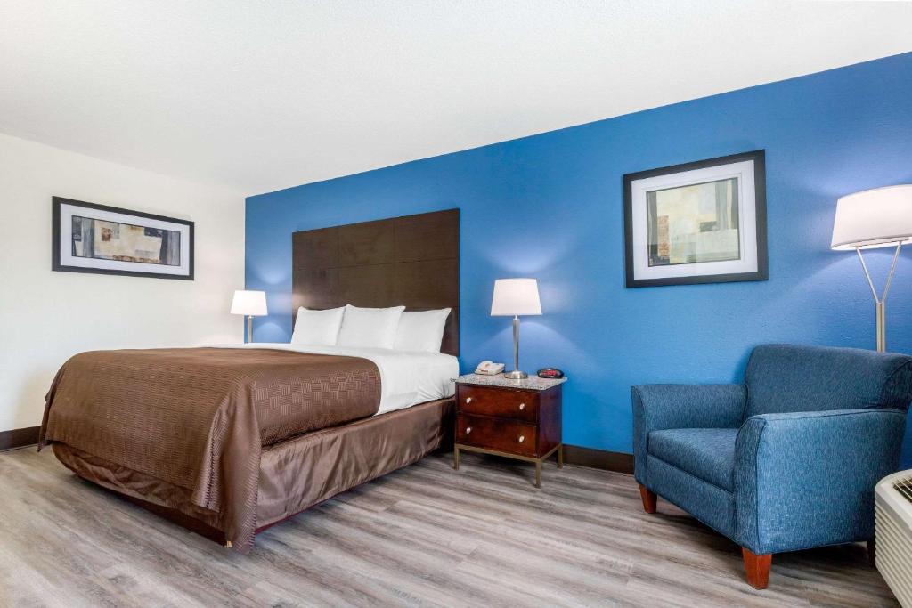 een slaapkamer met een bed en een blauwe muur bij Days Inn and Suites by Wyndham Oxford in Oxford