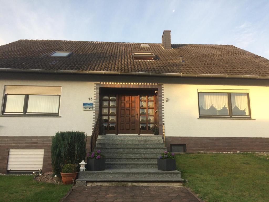 a white house with a brown door and stairs at Trixi in Kastellaun