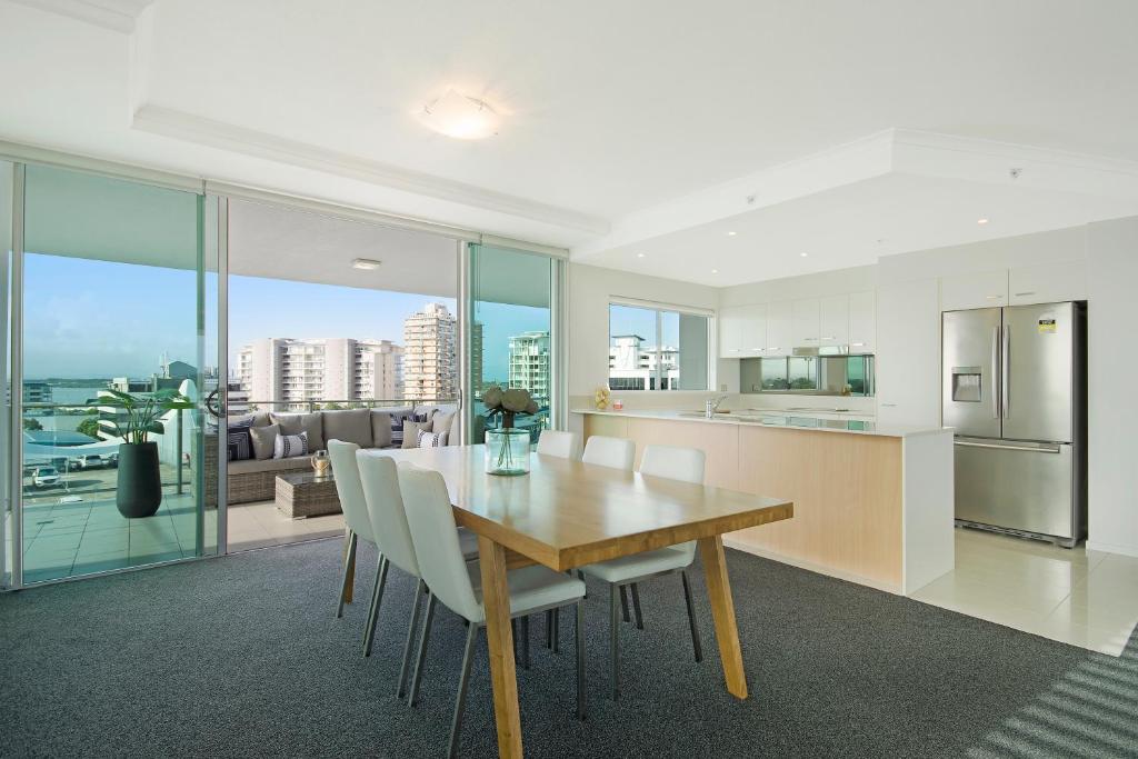 a kitchen with a table, chairs and a refrigerator at m1 Resort in Maroochydore
