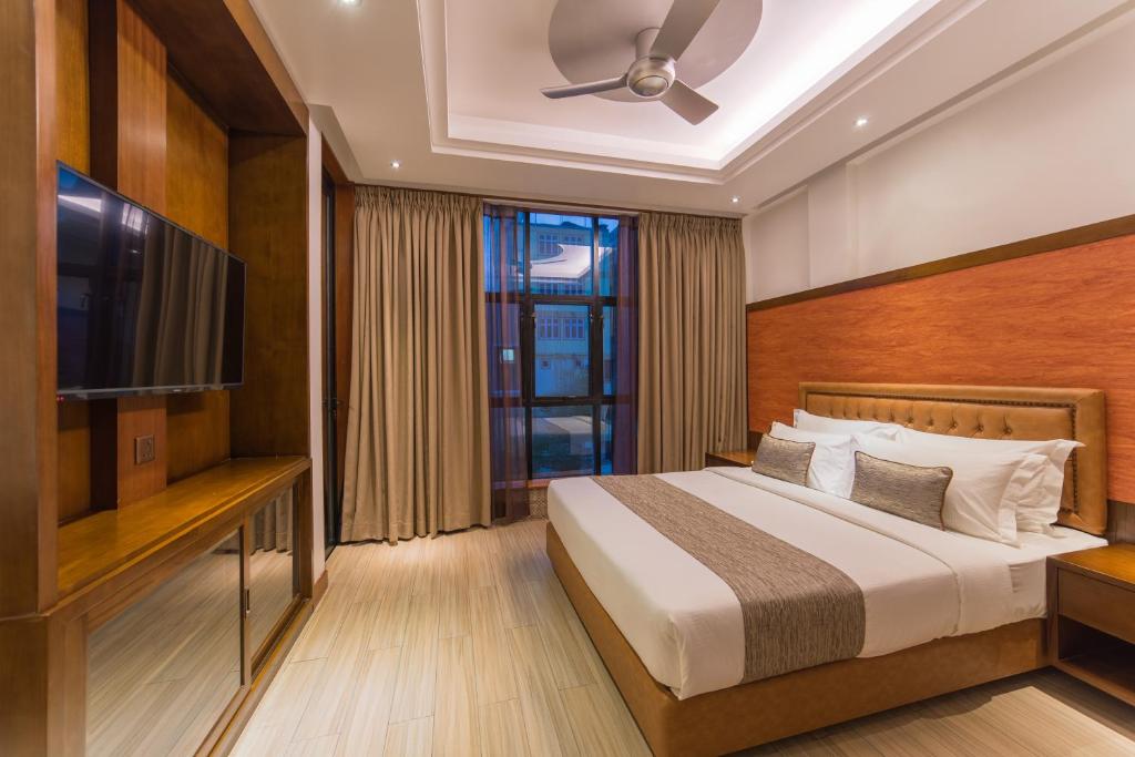- une chambre avec un lit et une télévision à écran plat dans l'établissement Samann Host, à Hulhumalé