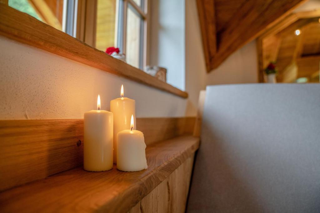 two white candles sitting on a wooden ledge next to a refrigerator at Almchalet Linharterhof in Haus im Ennstal
