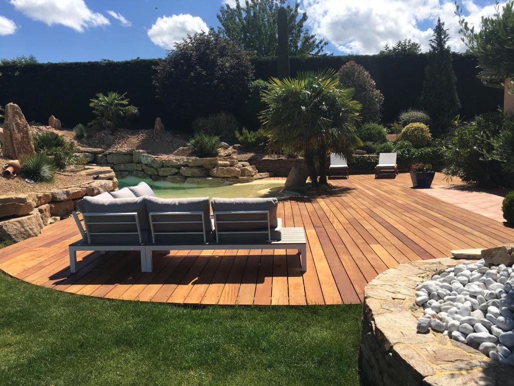 a bench on a wooden deck in a garden at Villa Chapulay in Valencin