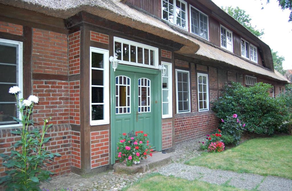 una casa de ladrillo con una puerta verde y flores en Ferienwohnungen Wulfshof II, en Schneverdingen