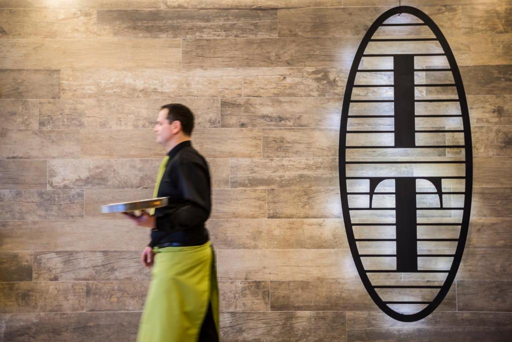 a man standing in front of a wall with a surfboard at Hotel Vinotel Gospoja in Vrbnik