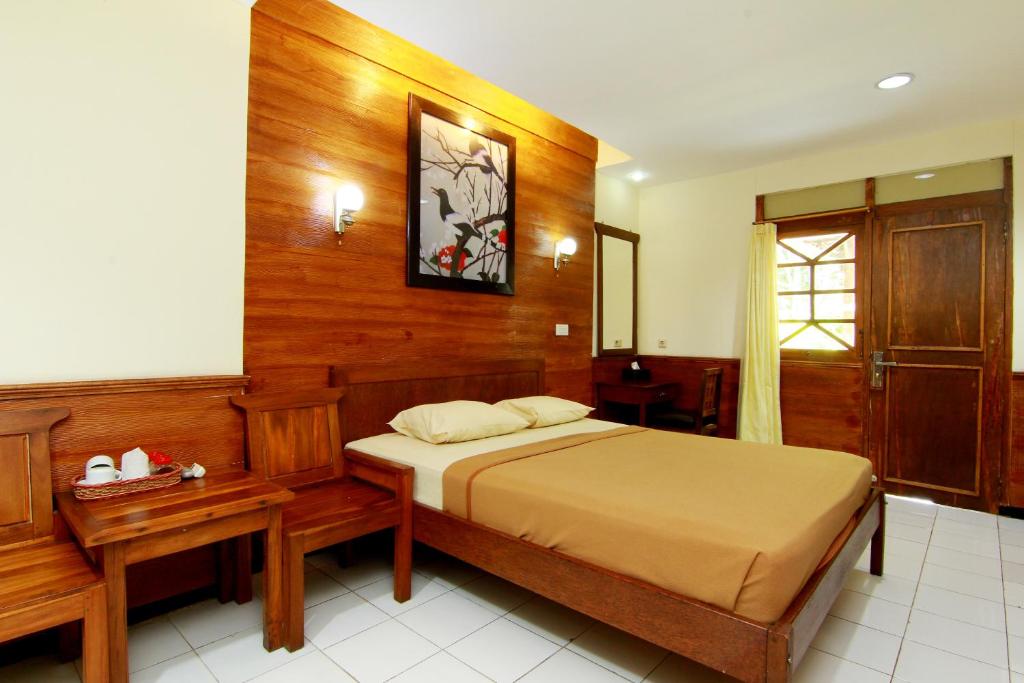 1 dormitorio con 1 cama y pared de madera en The Soemarsono Hotel, en Yogyakarta