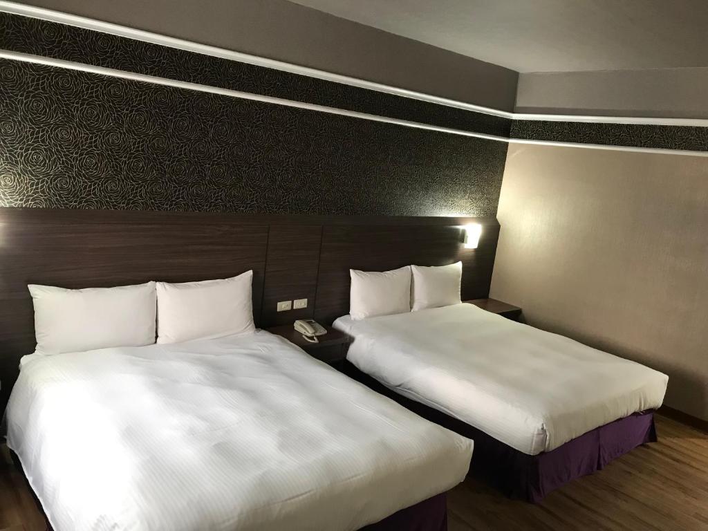 two beds in a hotel room with white sheets at Long Siang Hotel in Kaohsiung