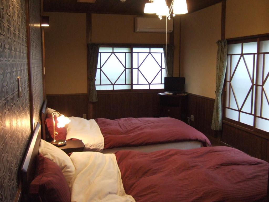 two beds in a room with two windows at Shinseikan in Nishiwaga