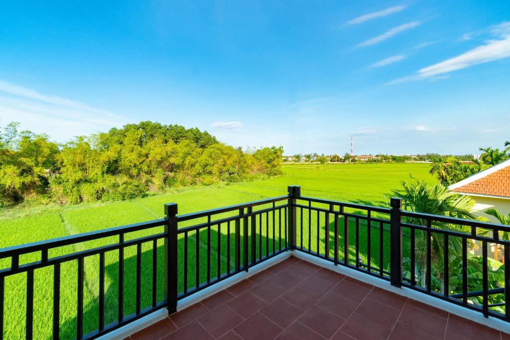 a balcony with a view of a green field at Lama Villa Hoi An in Hoi An