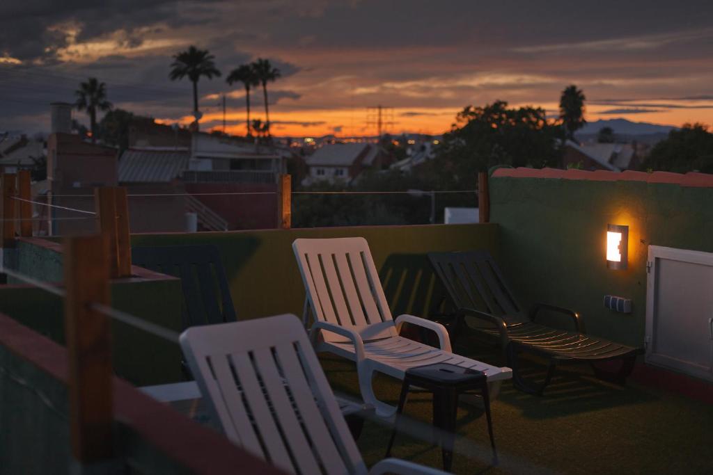 un grupo de sillas sentadas en un balcón al atardecer en La Casa Verde, en Murcia