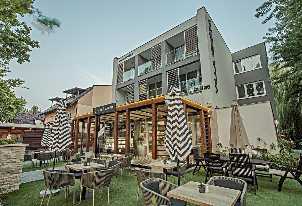 a restaurant with tables and chairs in front of a building at Villa Gréta in Siófok