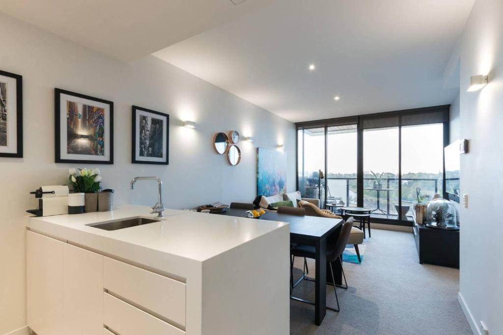 a kitchen with a sink and a table in a room at Laurent Balcony Views Steps from Laneway Vibes in Melbourne