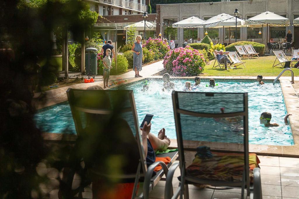 فندق غرين بارك بروغ في بروج: شخص يجلس على كرسي امام المسبح