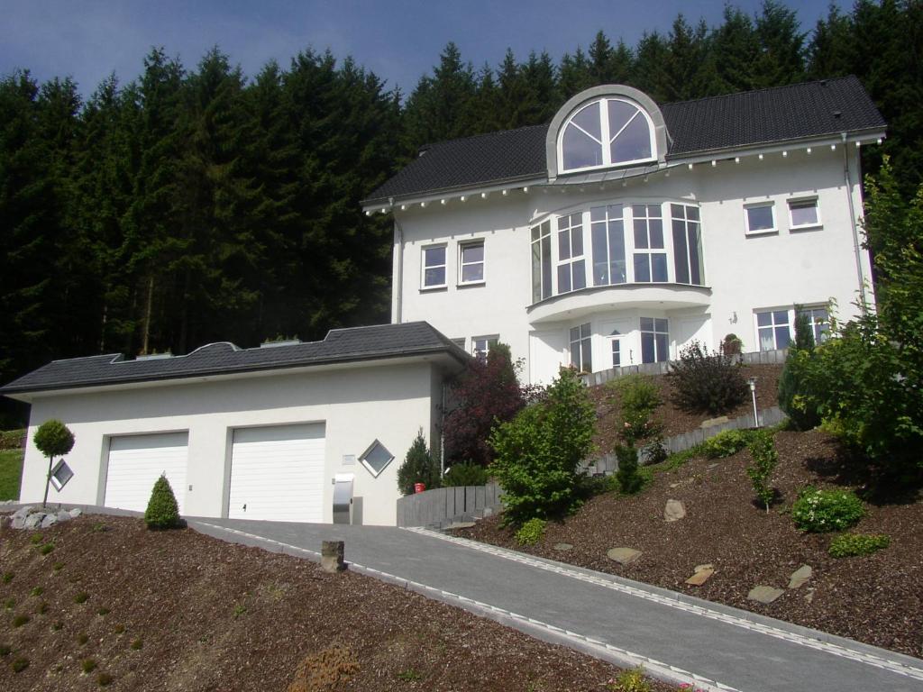 une maison blanche avec deux portes de garage dans l'établissement Ferienwohnung Haus Waldesruh, à Olsberg