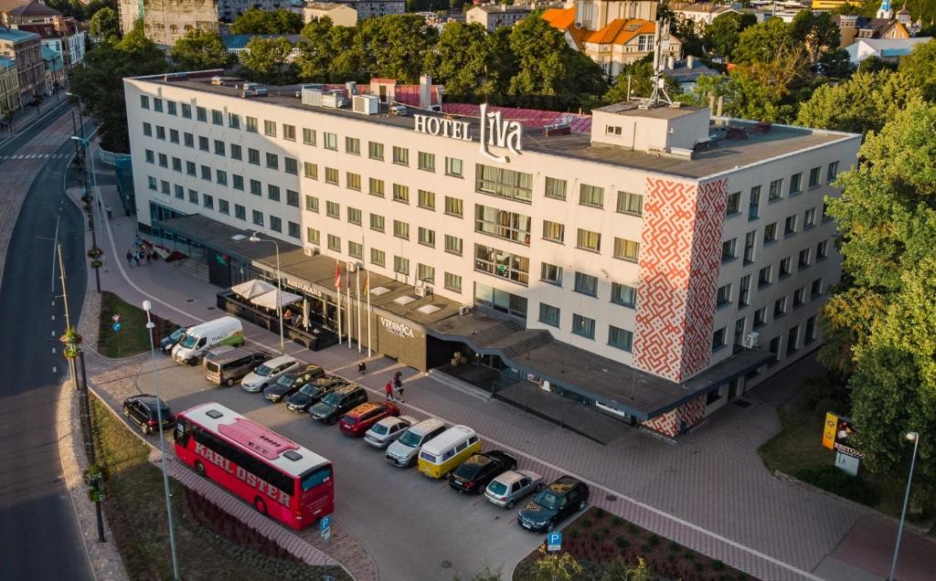 un gran edificio con coches estacionados en un estacionamiento en Liva Hotel en Liepāja