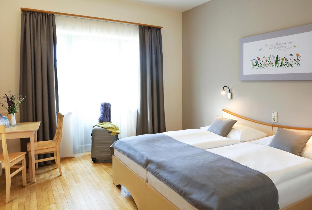 Habitación de hotel con 2 camas y escritorio en JUFA Hotel Pöllau - Bio Landerlebnis, en Pöllau