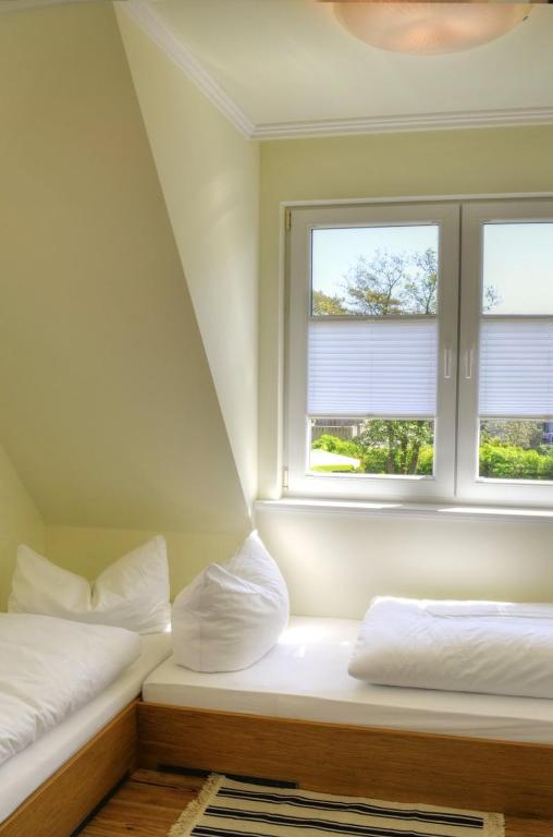 two beds in a room with two windows at Ferienhäuser Südwind in Hiddensee