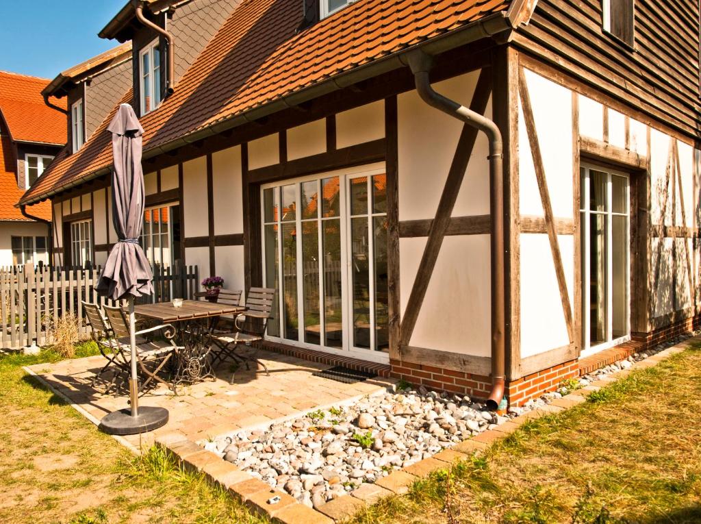 a house with an umbrella and a table and a bench at Ferienhäuser Südwind in Hiddensee