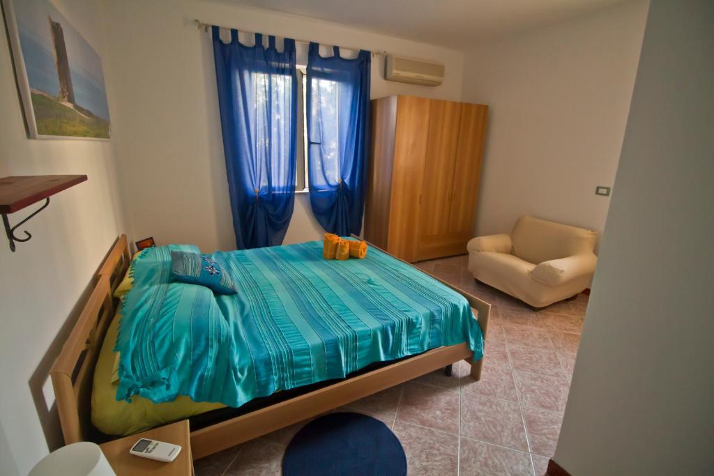 um pequeno quarto com uma cama e uma cadeira em B&B Sa Murighesa em San Vero Milis