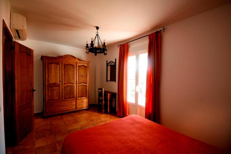 a bedroom with a bed and a window with red curtains at Casa Rural El Limonero in Los Naveros