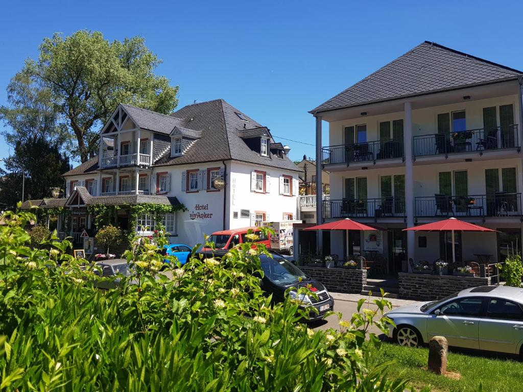 eine Gruppe von Gebäuden mit Autos auf einem Parkplatz in der Unterkunft Hotel Zum Anker in Neumagen-Dhron