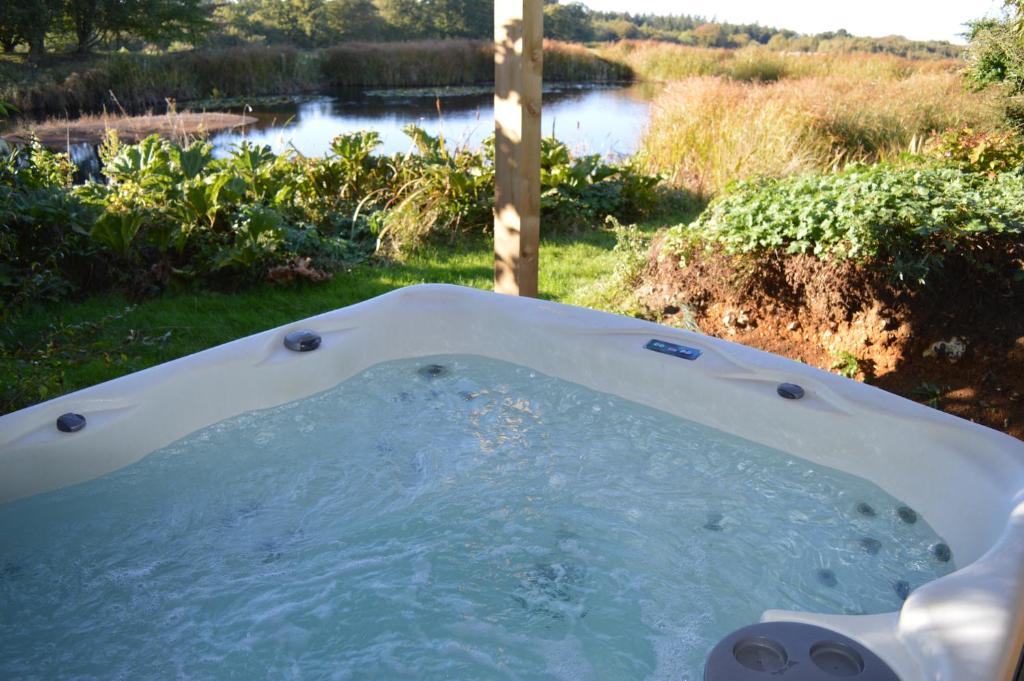 a jacuzzi tub with a view of a river at Rose Shepherds Hut in Badlesmere