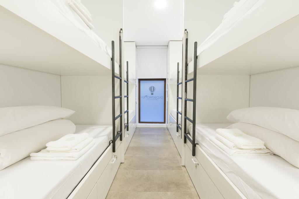 Habitación con camas blancas y puerta azul. en Globetrotter Hostel en León