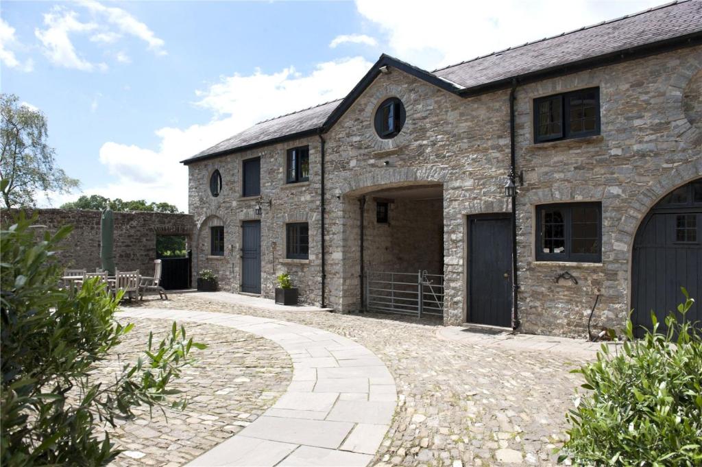 Außenansicht eines Steingebäudes mit Auffahrt in der Unterkunft The Stable Loft, Llwynhelig Manor in Llandeilo