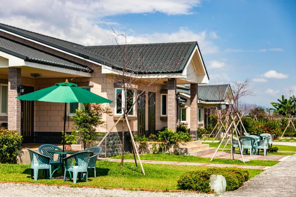 a house with a table and chairs and an umbrella at Countryside B&amp;B in Ruisui