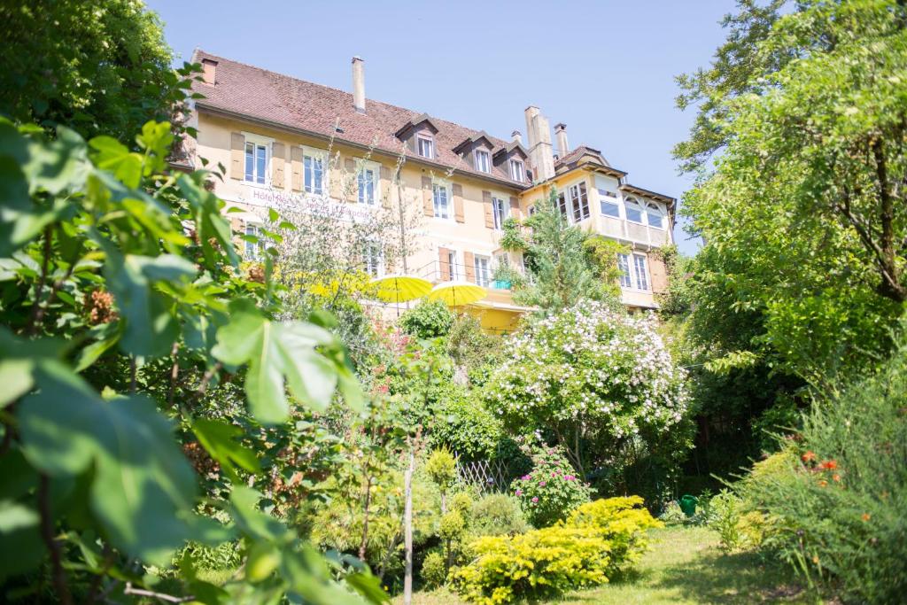 a building with a garden in front of it at Hôtel de la Béroche in Saint Aubin Sauges