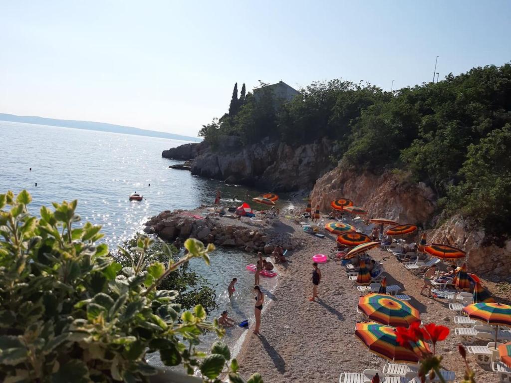 a group of people on a beach with umbrellas at grabrova cove in Novi Vinodolski