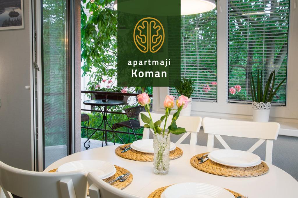 Apartmaji Koman في بليد: طاولة بيضاء عليها صحون بيضاء وزهور