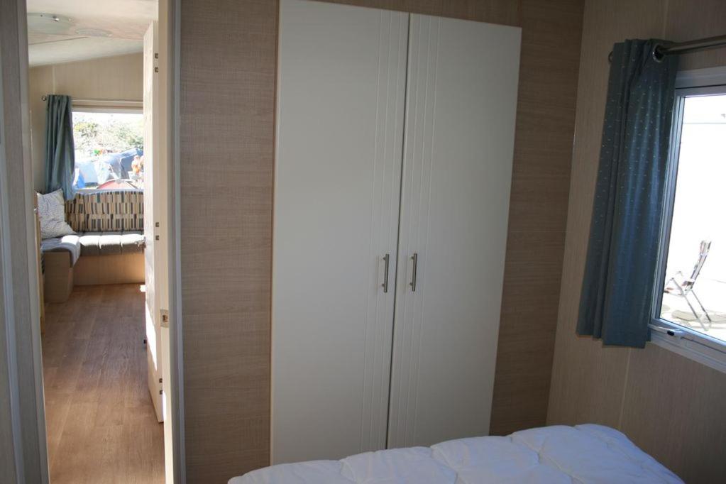 Chalet De Duinberg في آيماودن: غرفة نوم مع سرير وخزانة بيضاء كبيرة