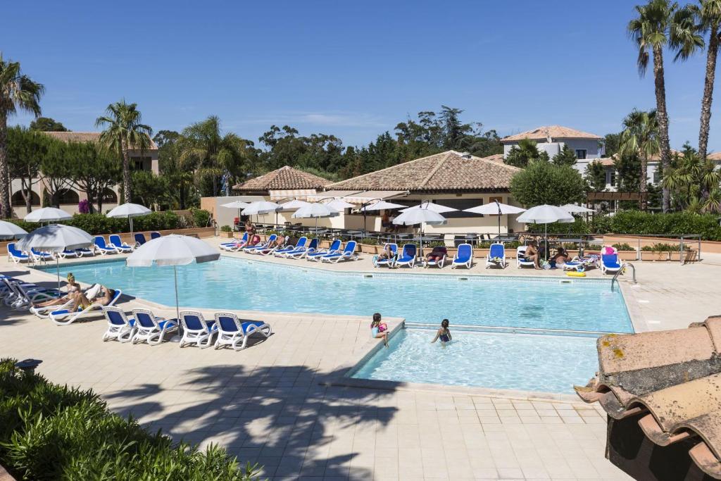 a swimming pool with chairs and people in a resort at Vacancéole - Résidence Sognu di Mare in Linguizzetta