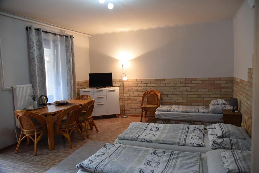 TolnaにあるSzilvia Panzióのベッド3台、テーブル、テレビが備わる客室です。