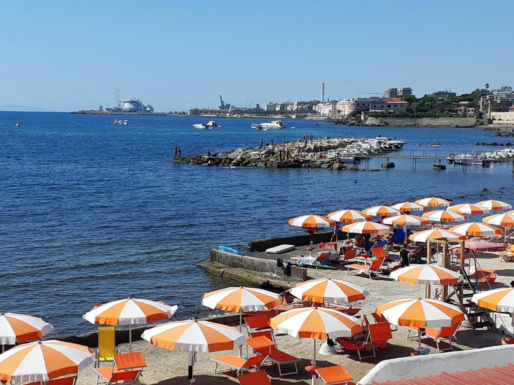 een bos parasols op een strand naast het water bij Guest house al mare in Civitavecchia