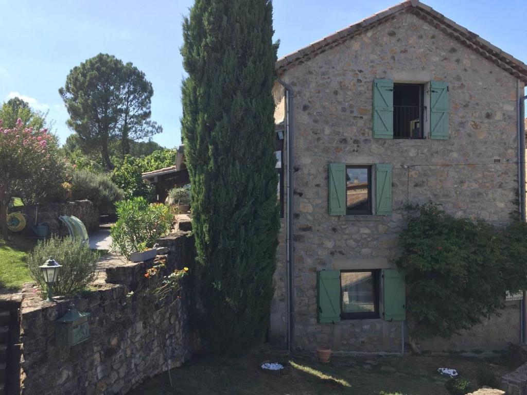 una antigua casa de piedra con un gran árbol en Maison de Sao en pierres, en Lablachère