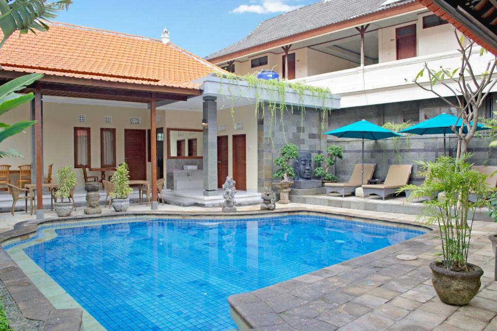 a swimming pool in front of a house at Flamboyan Hotel in Kuta
