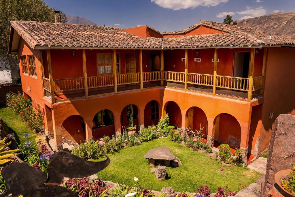 ein orangefarbenes Haus mit Garten davor in der Unterkunft Luna Rumi Hotel-Lodge Urubamba in Urubamba